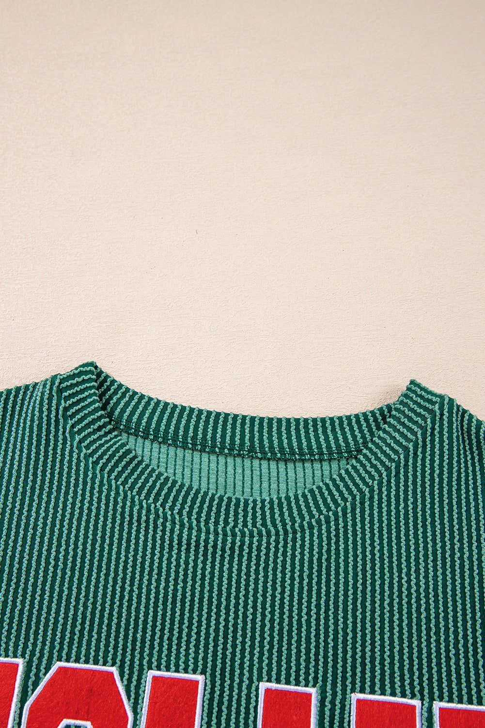 Close-up of neckline on green Evergreen JOLLY Corded Top. Ribbed knit detail ideal for cozy holiday wear from Faith & Co. Boutique.
