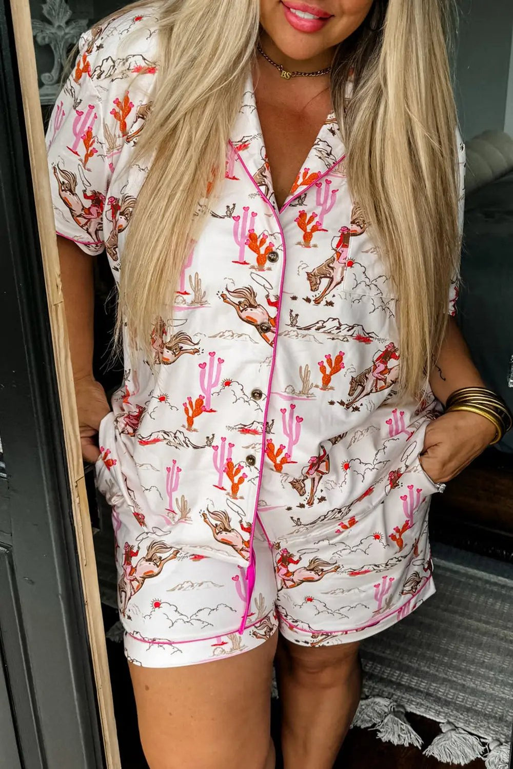 Close-up of White Cowgirl Country Print Pajamas Set featuring cowgirl and cactus illustrations in pink and red. Shop White Cowgirl Country Print Pajamas Set at Faith & Co. Boutique.