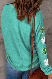 a woman wearing a green sweater with shamrocks on it