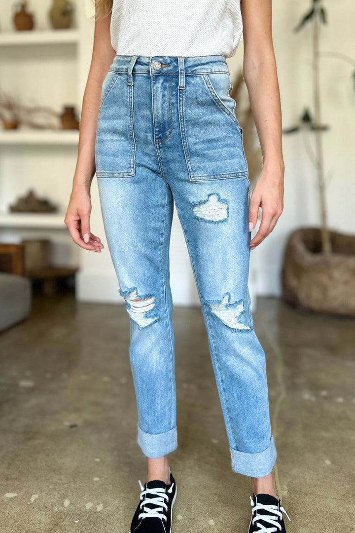 a woman standing in a room wearing a pair of ripped jeans