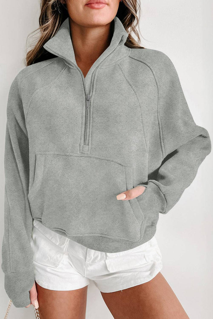 a woman wearing a gray sweatshirt and white shorts