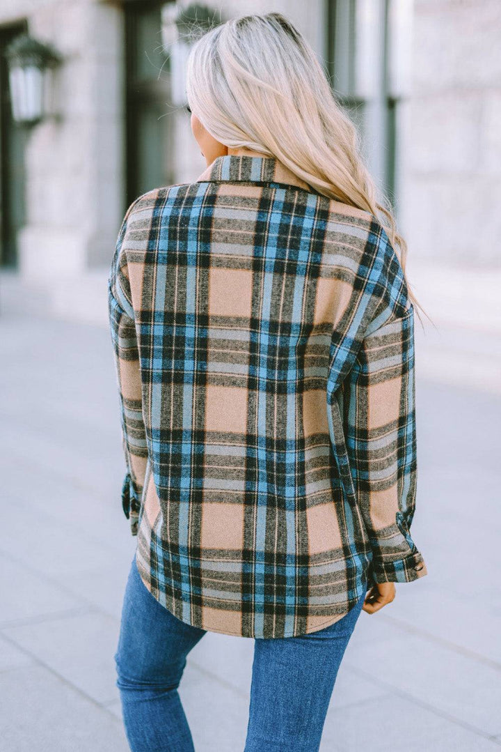 a woman standing on a sidewalk wearing a plaid jacket