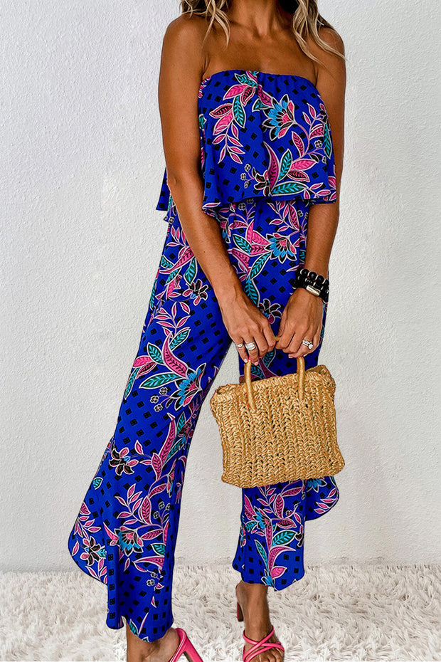 a woman in a blue patterned jumpsuit holding a straw bag