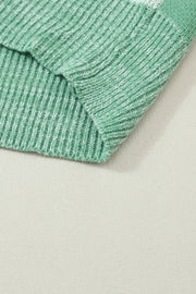 a close up of a green sweater on a white surface