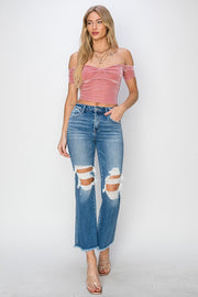 a woman wearing a pink top and ripped jeans