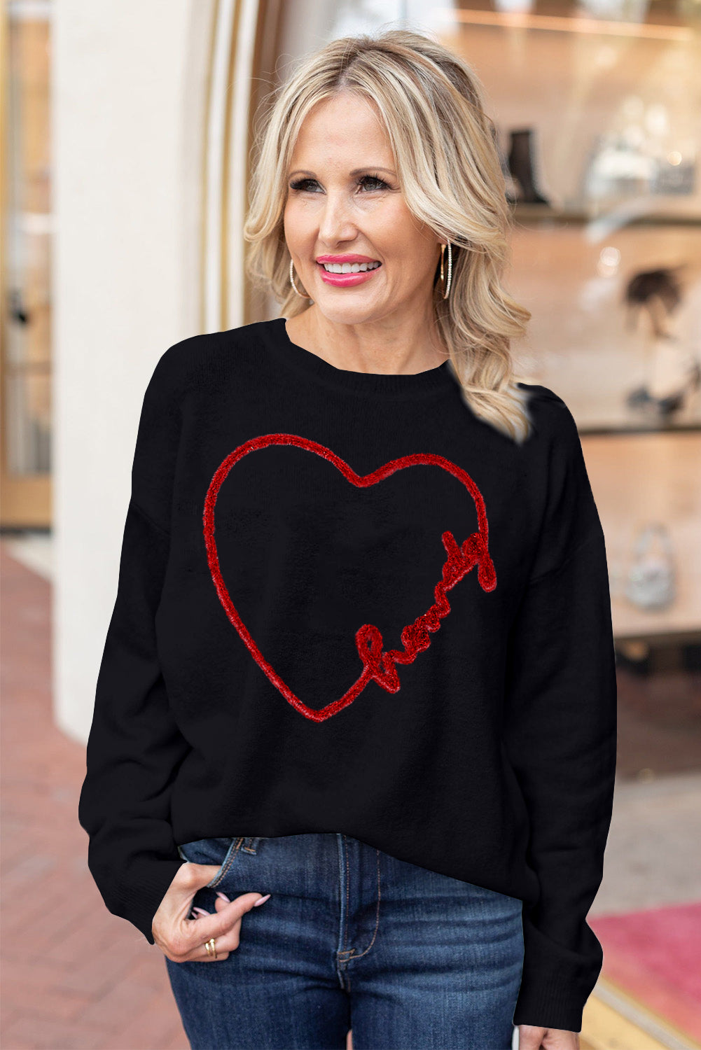 a woman wearing a black sweater with a heart drawn on it