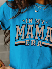 a woman wearing a blue shirt that says in my mama era