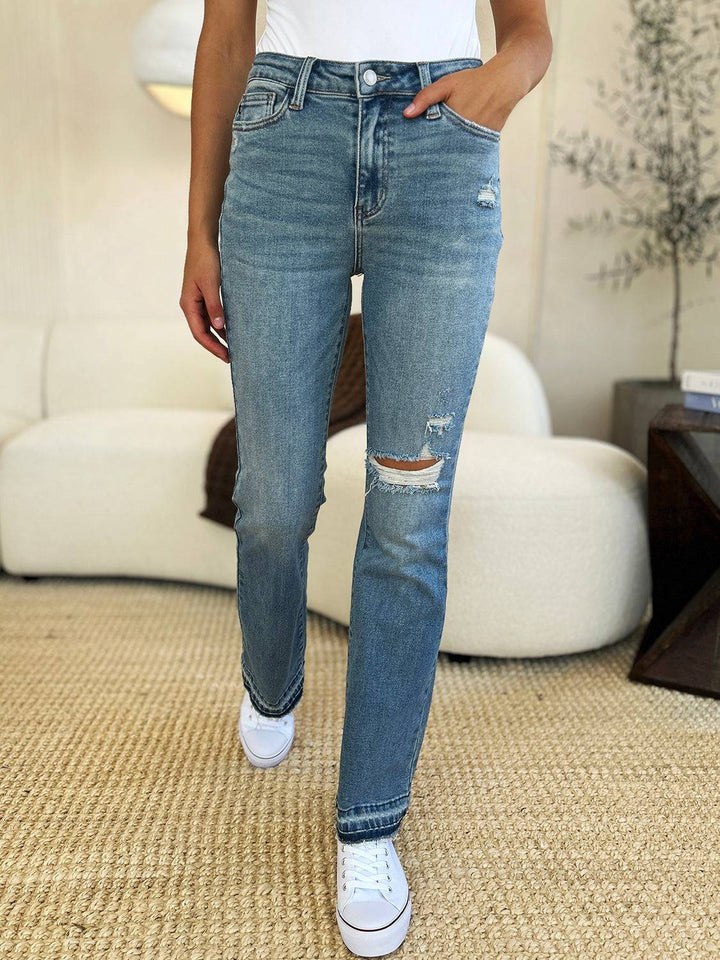 a woman standing in a living room wearing ripped jeans