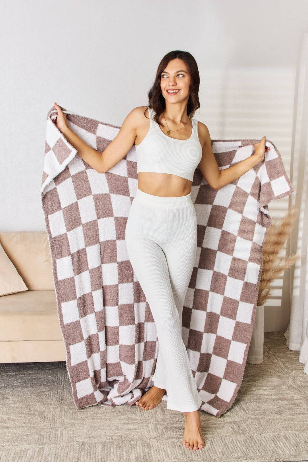 a woman holding a checkered blanket in a room