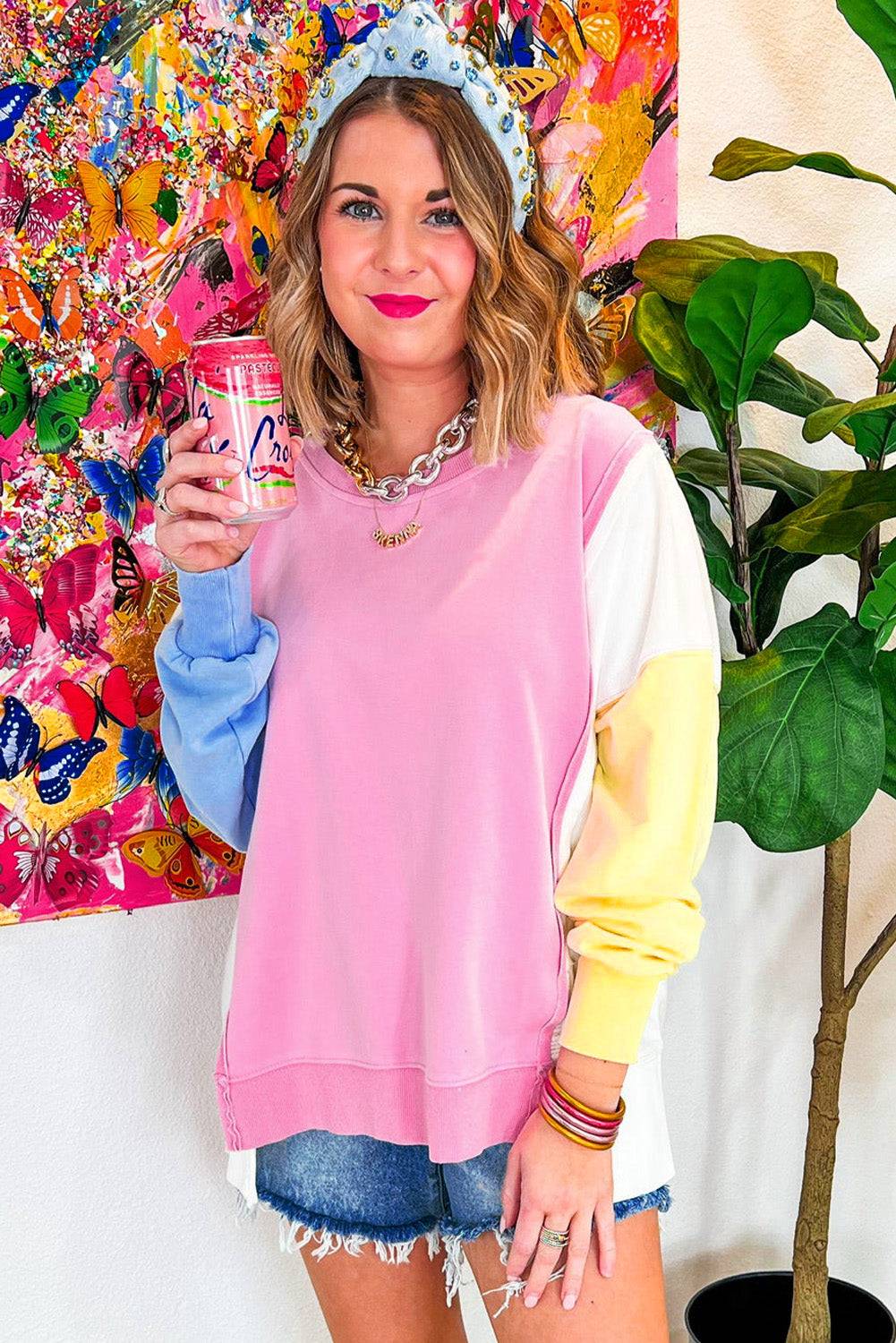 a woman holding a can of soda in front of a painting