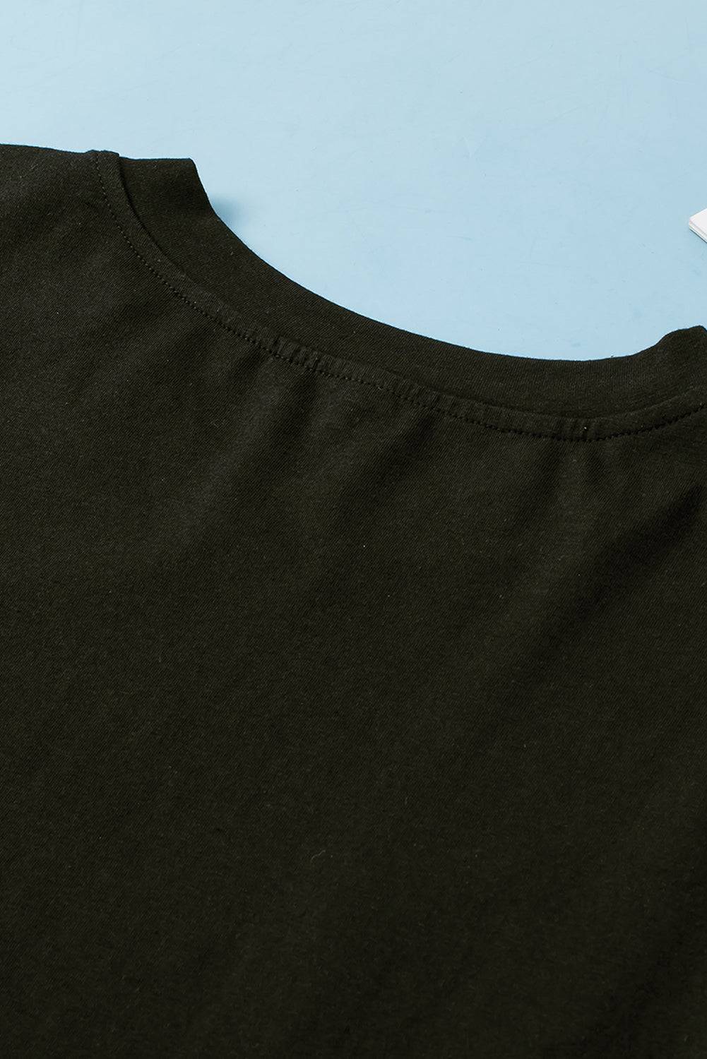 a black t - shirt laying on top of a blue surface