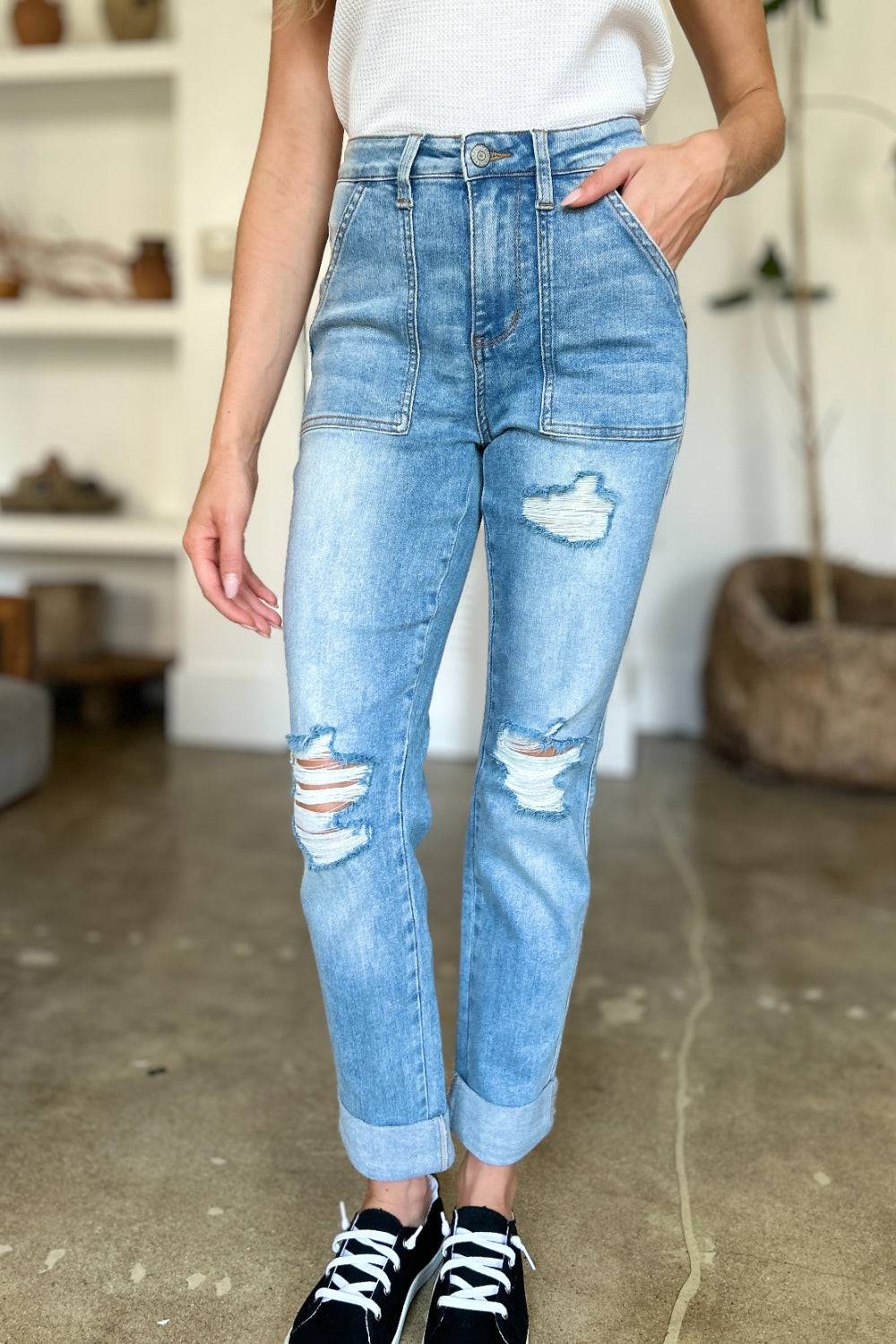 a woman standing in a room wearing ripped jeans