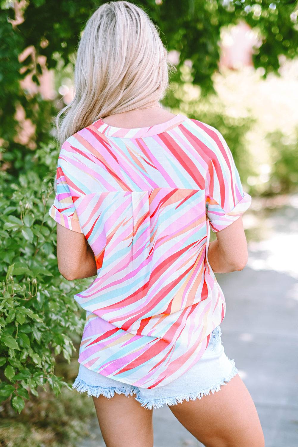 a woman wearing a colorful striped shirt and denim shorts