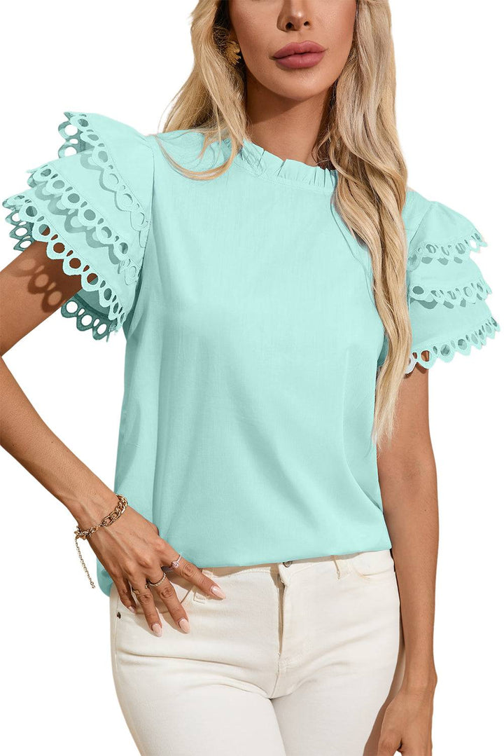 a woman wearing a light blue top with scalloped sleeves