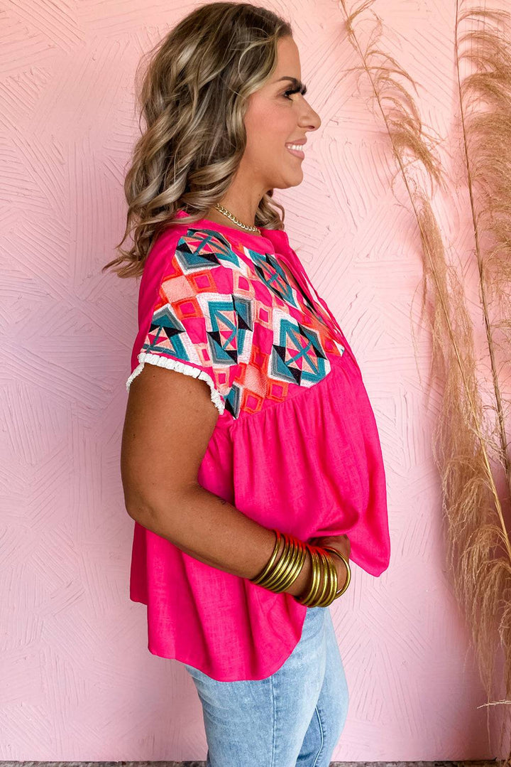 a woman standing in front of a pink wall