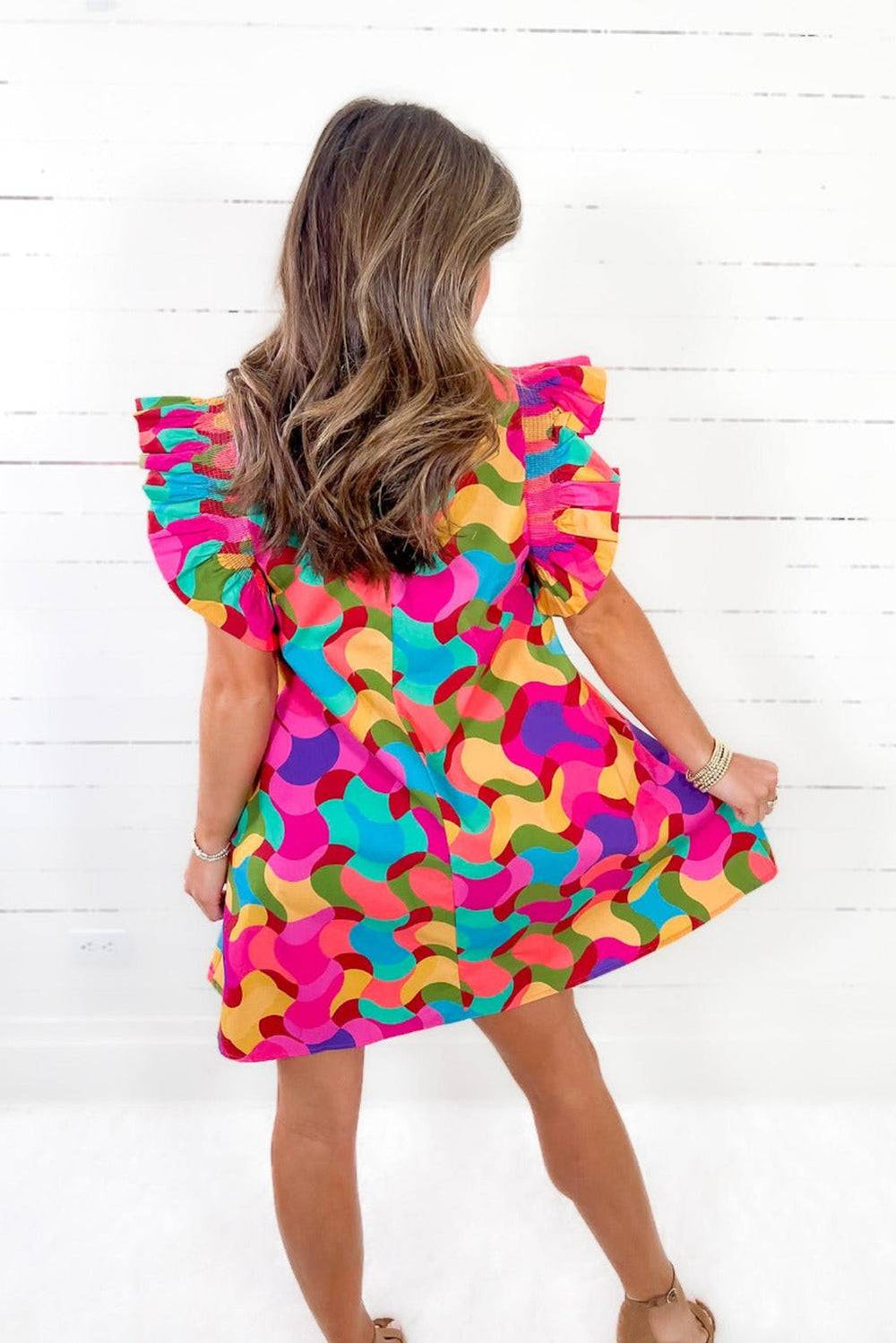 a woman in a colorful dress is standing in front of a white wall