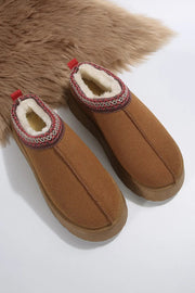 a pair of brown slippers sitting on top of a furry rug