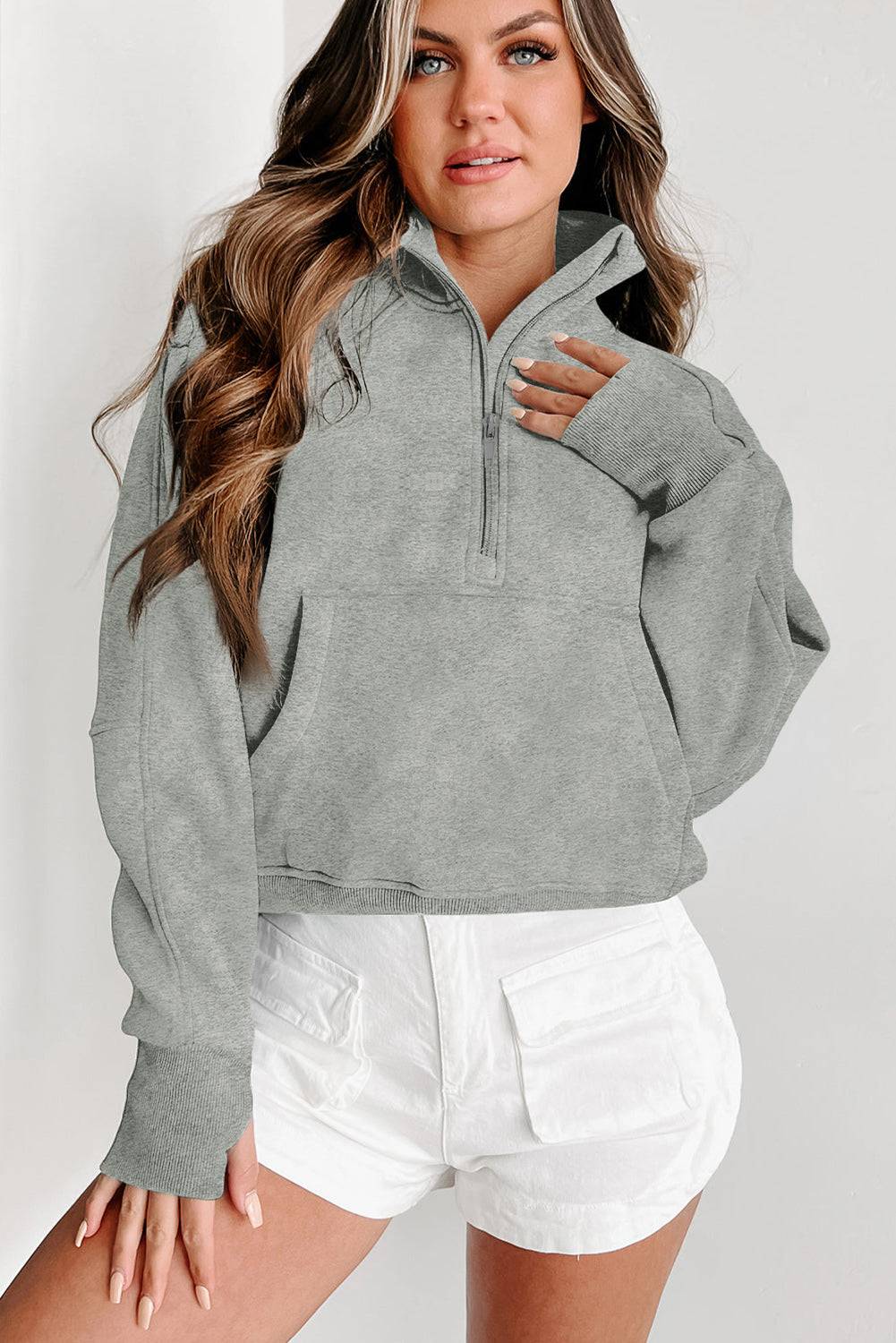 a woman wearing a grey sweatshirt and white shorts