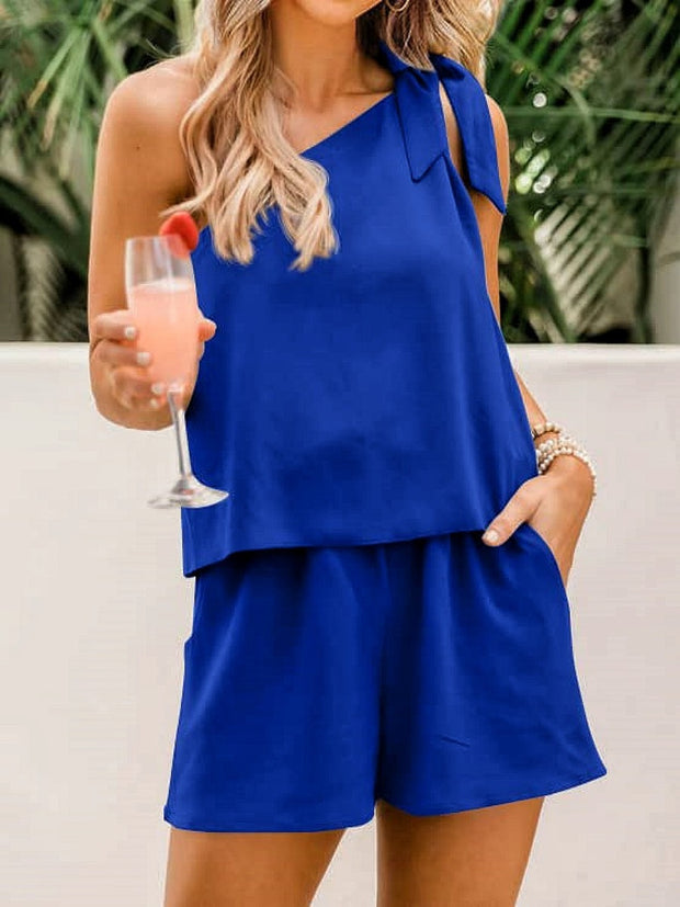 a woman in a blue rom and shorts holding a drink