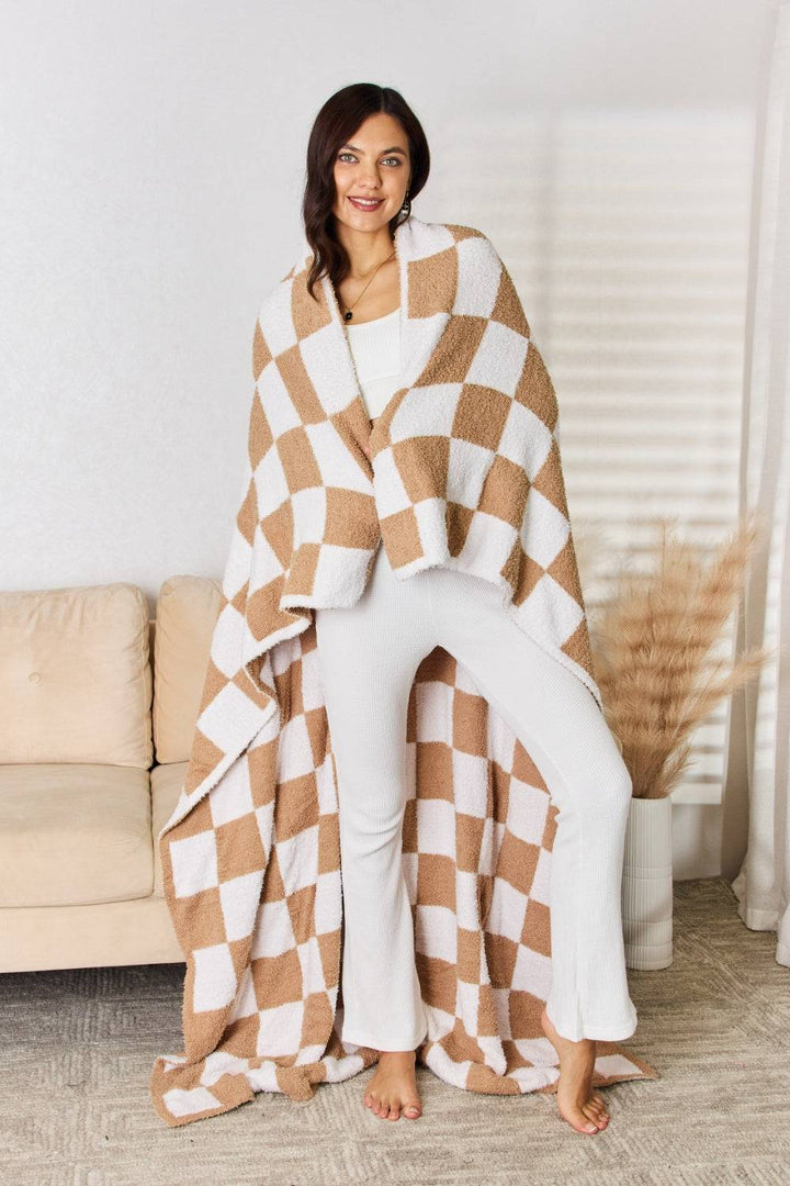 a woman standing in front of a couch wearing a brown and white checkered blanket