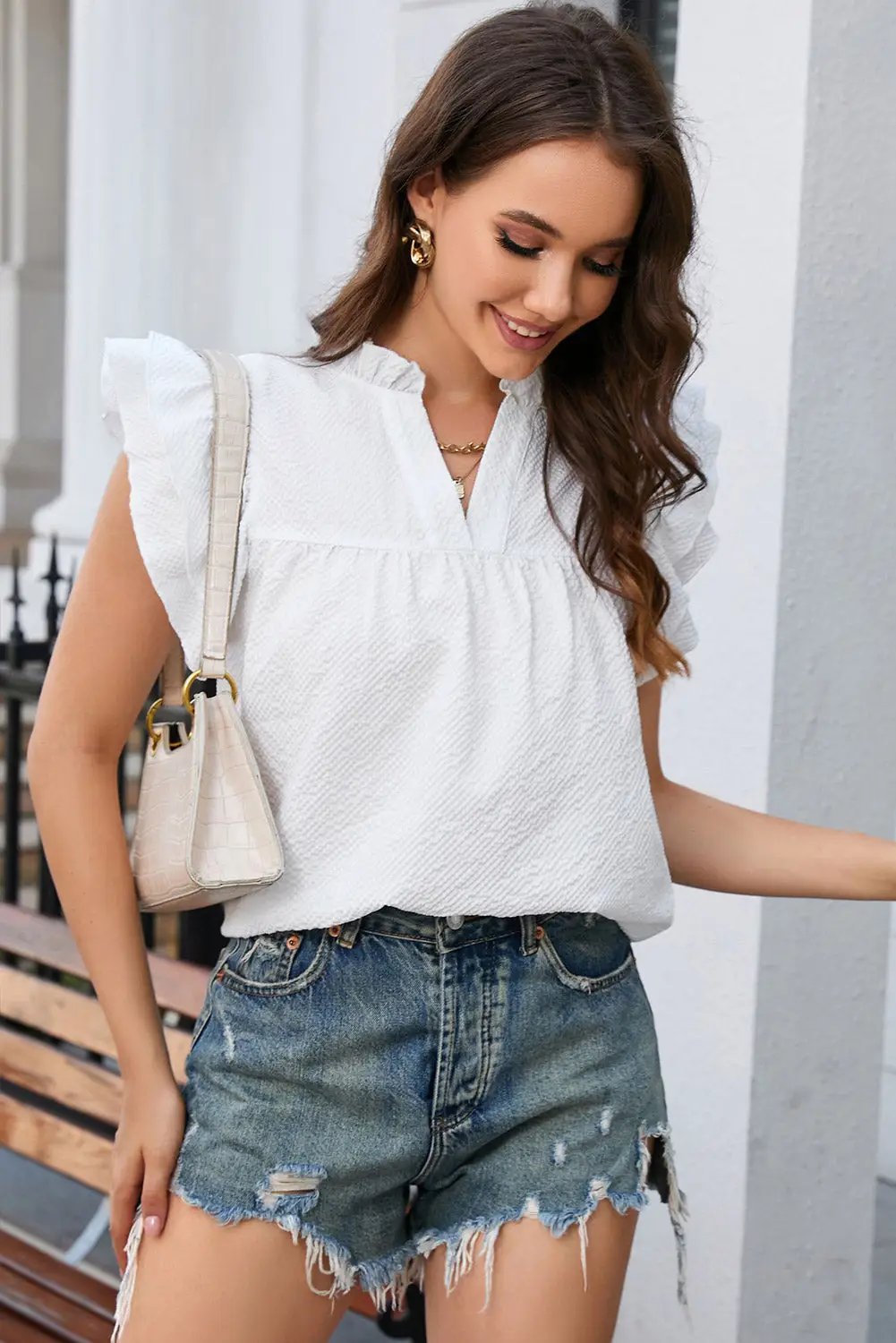 a woman wearing a white top and denim shorts