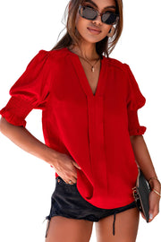 a woman wearing a red blouse and black shorts