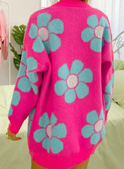 a woman wearing a pink sweater with blue flowers on it