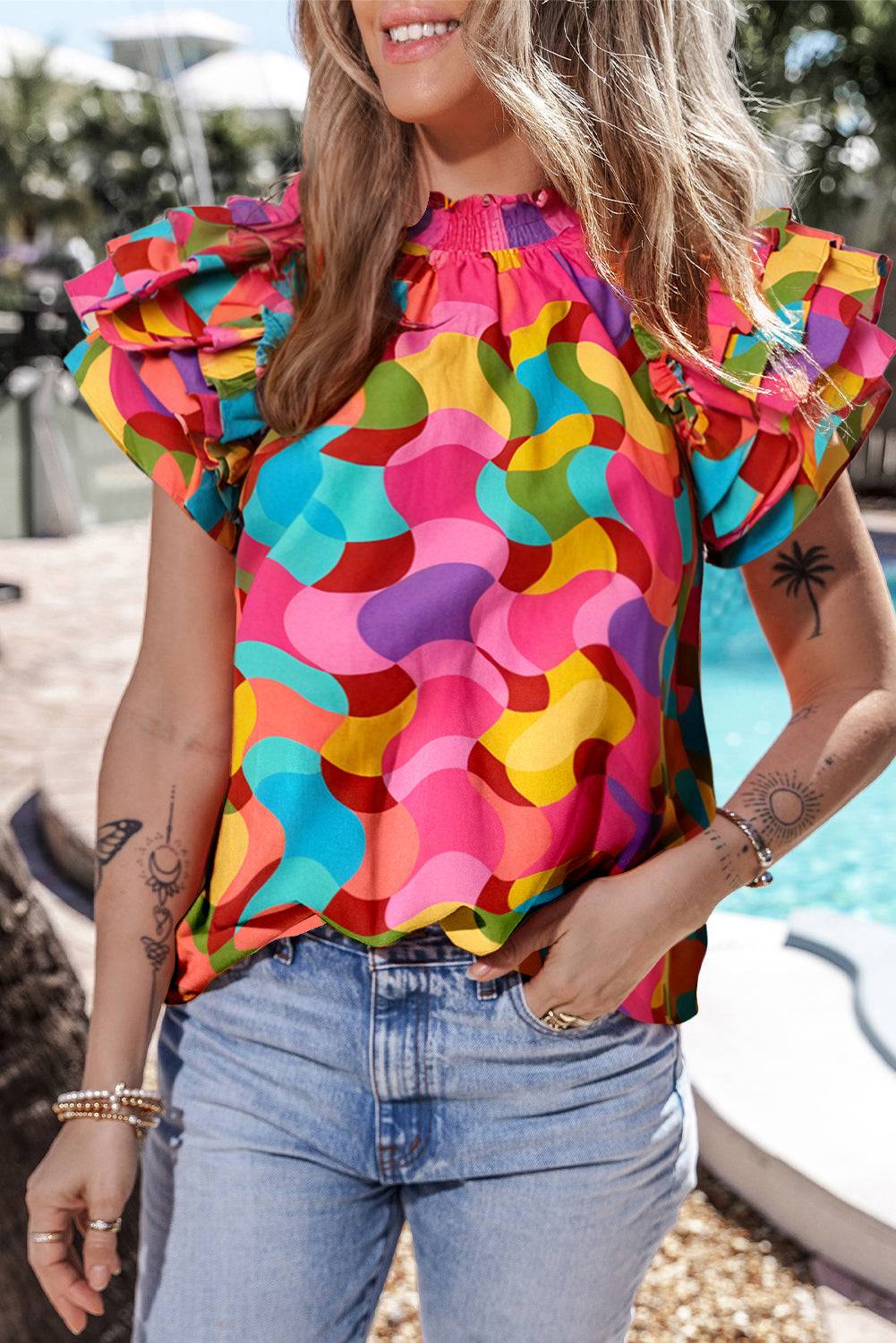 a woman wearing a colorful top standing next to a pool