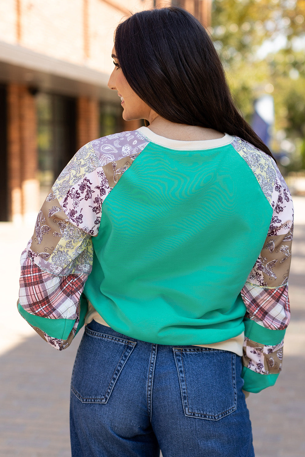 Back view of Aruba Blue Plaid Vintage Paisley Patchwork Long Sleeve Raglan Top showing colorful patchwork sleeves. Shop at Faith & Co. Boutique.