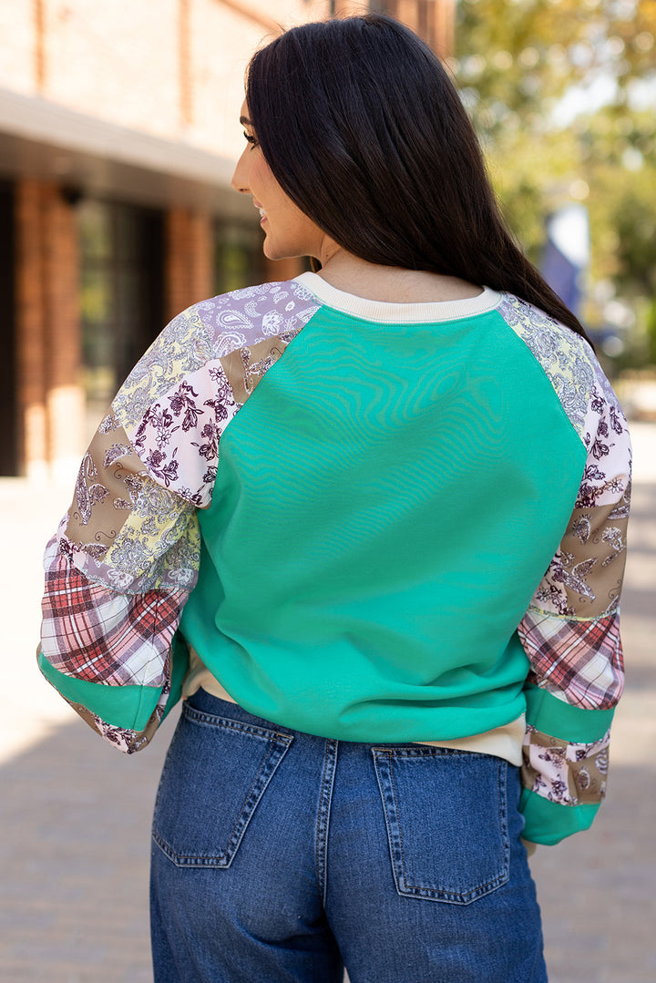 Back view of Aruba Blue Plaid Vintage Paisley Patchwork Long Sleeve Raglan Top showing colorful patchwork sleeves. Shop at Faith & Co. Boutique.