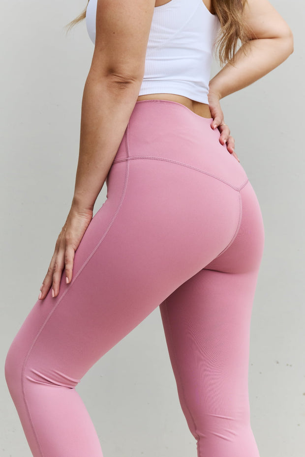 a woman in a white tank top and pink leggings