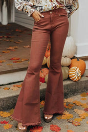 a woman standing in front of a door wearing a white blouse and brown pants
