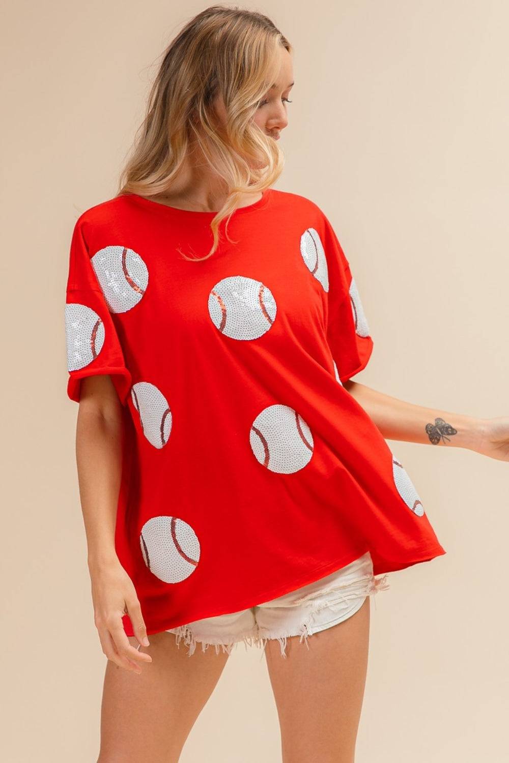 a woman wearing a red shirt with baseballs on it