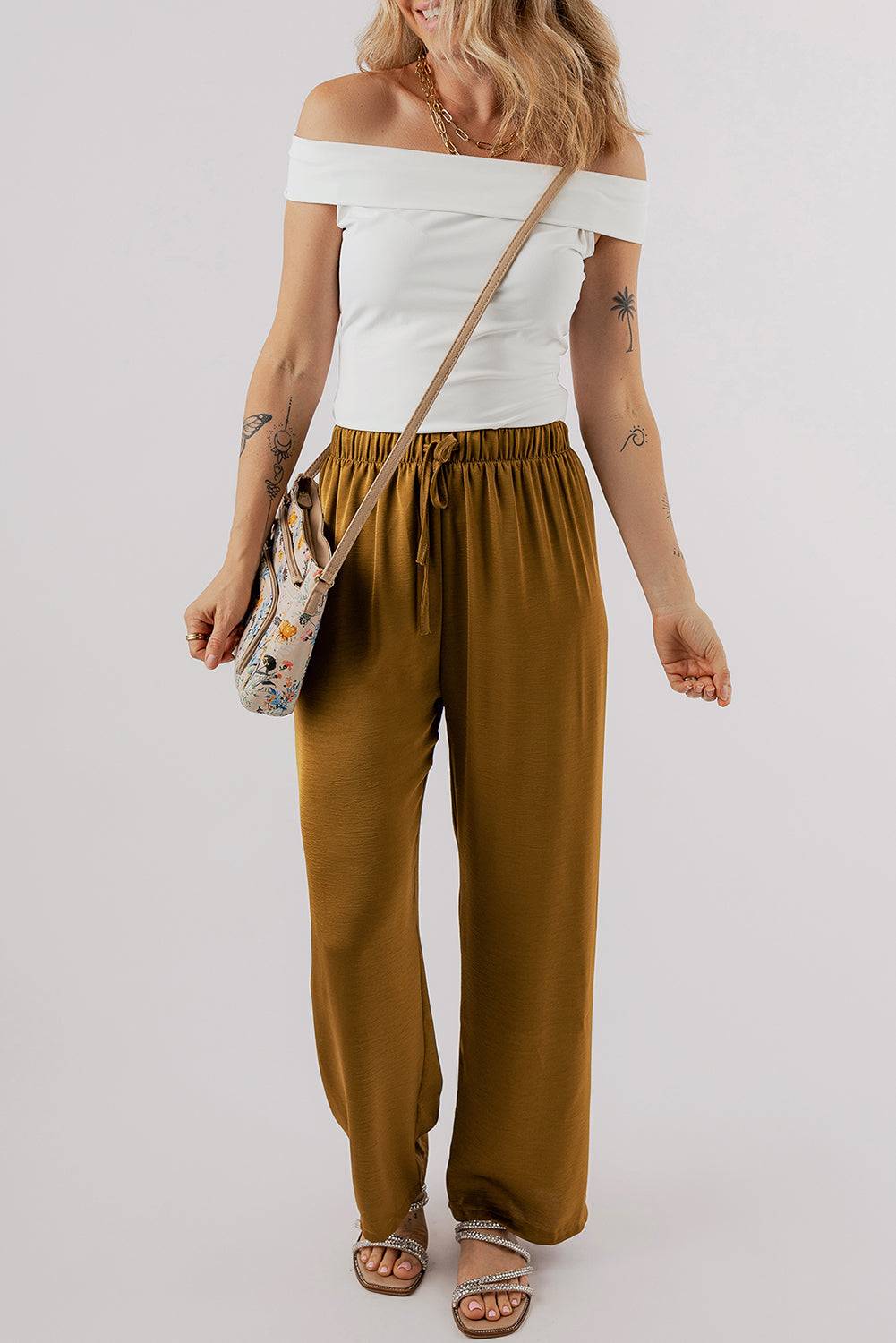 a woman wearing a white top and brown pants