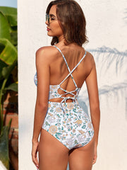 a woman in a white and blue floral print one piece swimsuit