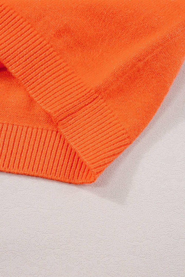 an orange sweater laying on top of a white surface