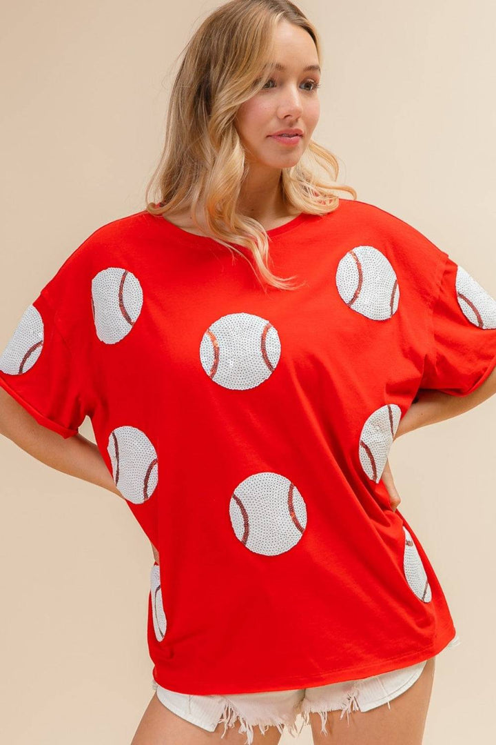 a woman wearing a red shirt with baseballs on it