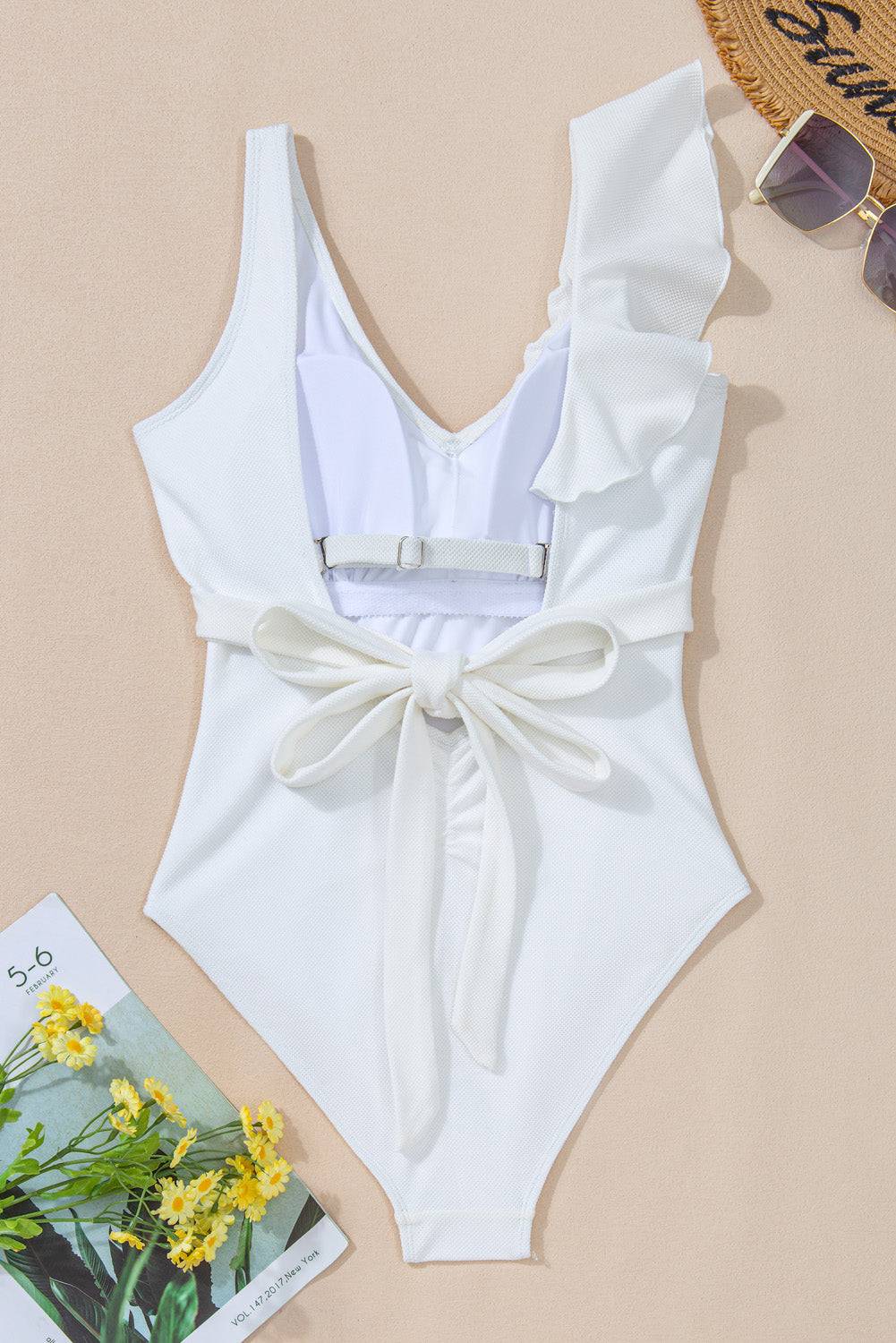 a white one piece swimsuit with a bow on the back