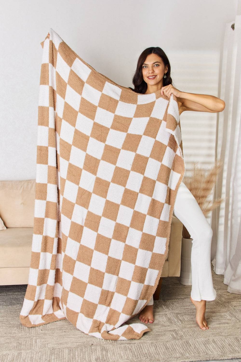 a woman is holding up a checkered blanket