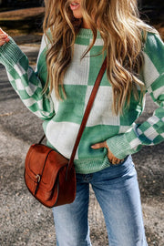 a woman wearing a green and white sweater and jeans