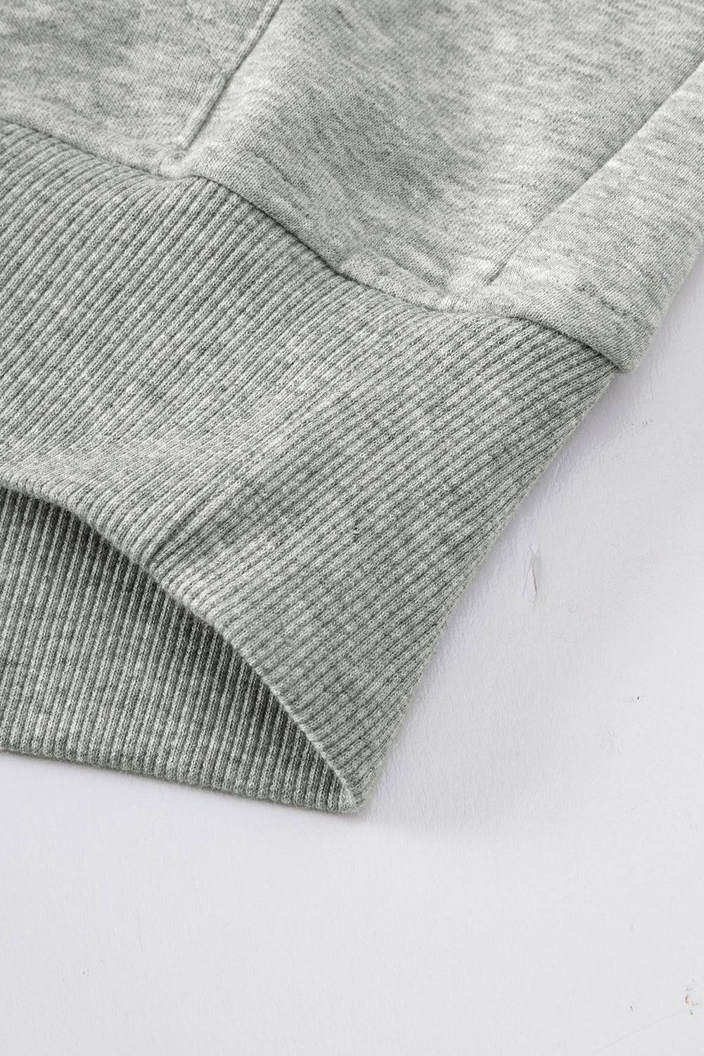 a close up of a gray sweater on a white surface