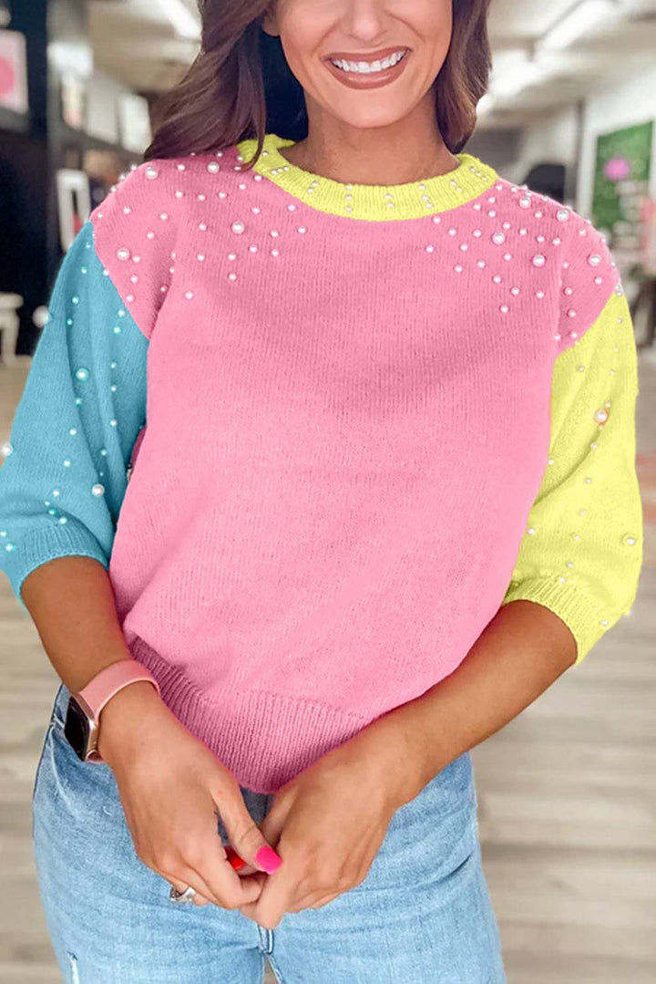 a woman wearing a pink and blue sweater and jeans