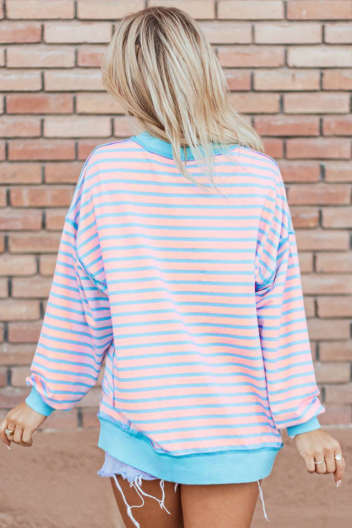 a woman wearing a pink and blue striped sweatshirt