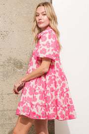 a woman in a pink dress standing next to a wall