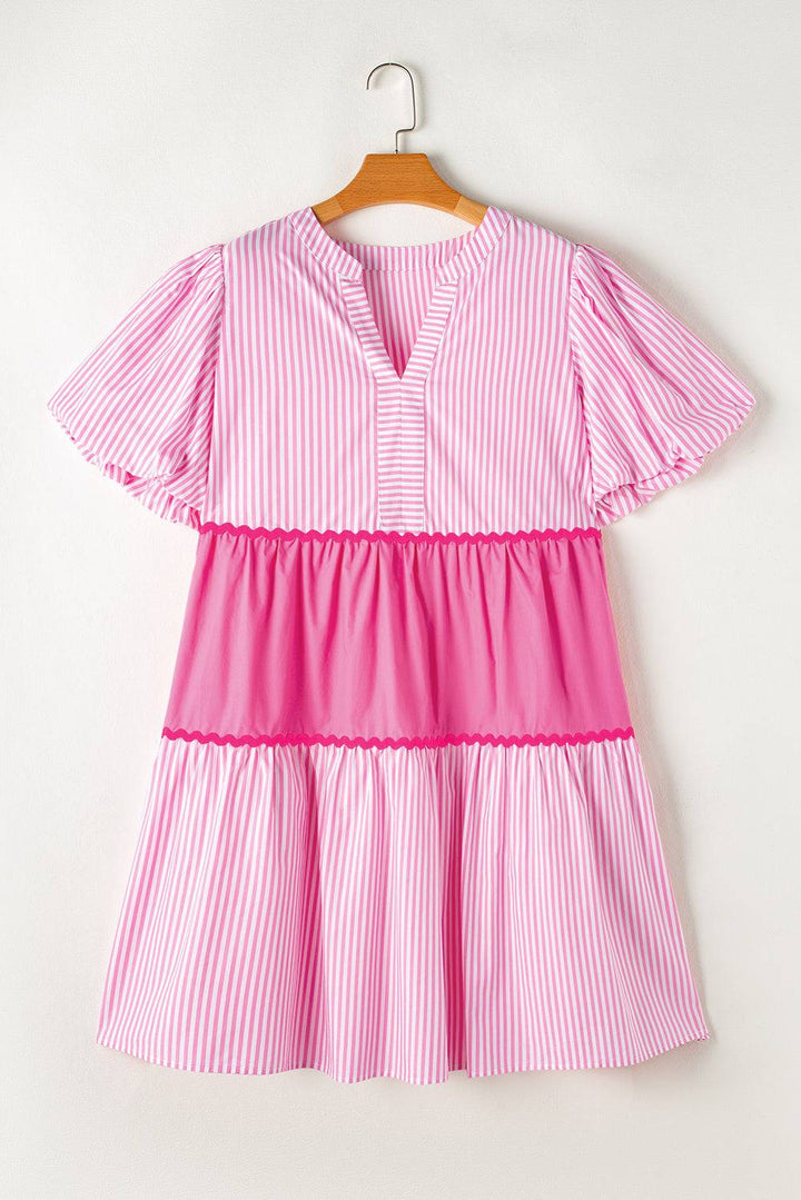 a pink and white striped dress hanging on a hanger