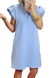 a woman in a blue dress talking on a cell phone
