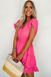 a woman in a pink dress holding a straw bag