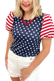 a woman wearing a patriotic shirt and white shorts