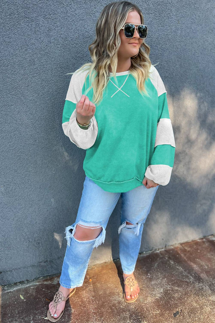 a woman wearing ripped jeans and a green sweater