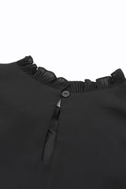 a close up of a black dress with a ruffled collar
